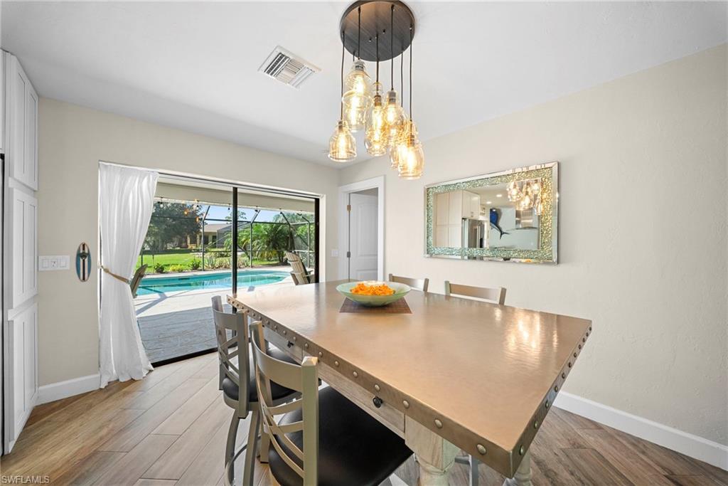 Dining area with wood-finish flooring and a multi-bulb chandelier
