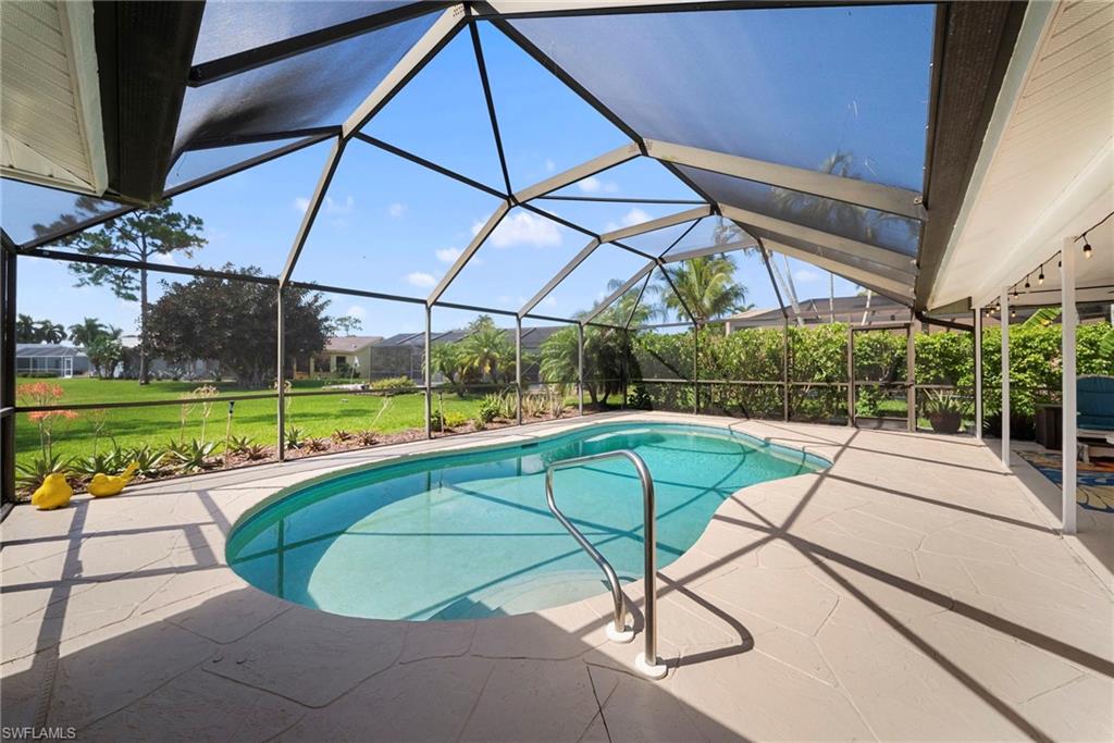 Screened-in outdoor pool featuring an irregular shape, integrated stairs, and a stainless steel grab rail