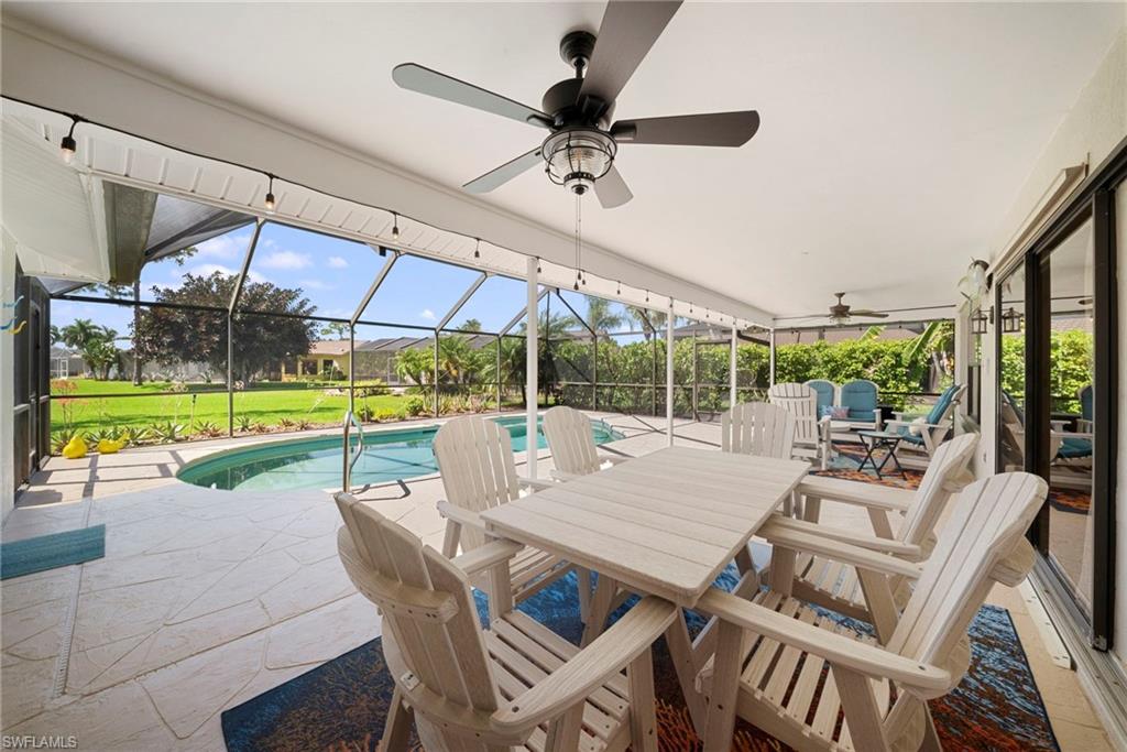 Screened lanai featuring a ceiling fan with light fixture, string lighting, and a paved pool deck with a kidney-shaped pool