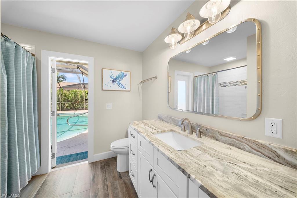 Bathroom featuring a white vanity with extensive counter space, an integrated sink, and wood-finish flooring