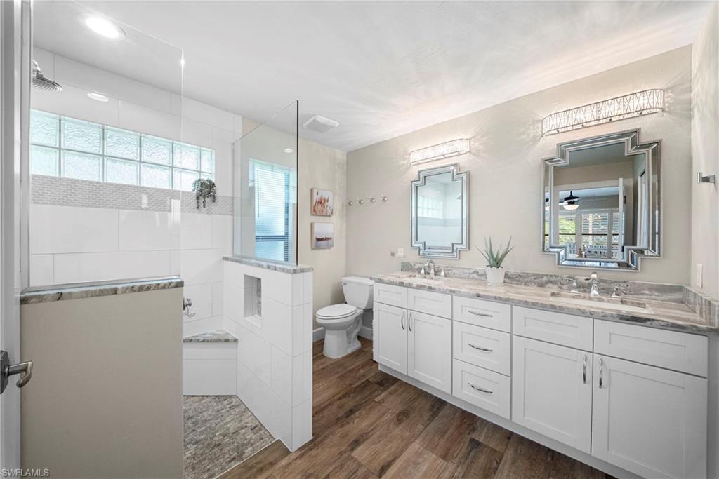 Spacious bathroom featuring a frameless glass shower enclosure with a built-in bench, glass block window, and mosaic tile accent