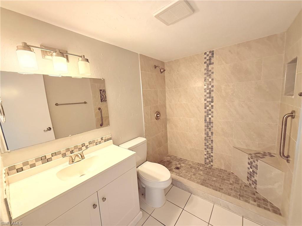Walk-in shower with neutral-toned tiling, a decorative mosaic vertical accent, and a built-in bench