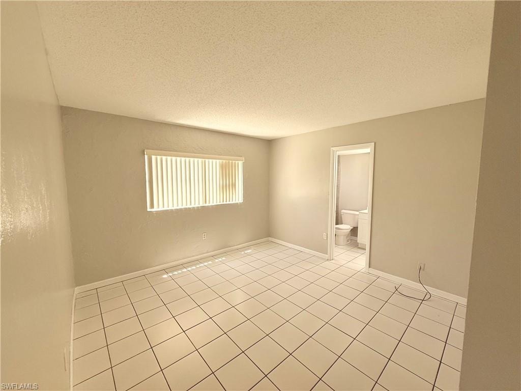 Spacious interior room featuring light-colored walls and a window with horizontal blinds