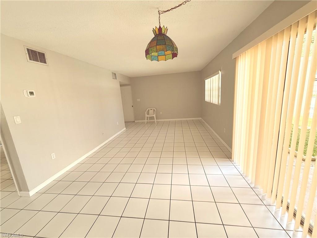 Spacious interior featuring ceramic tile flooring, light gray wall paint, and a stained-glass style ceiling light fixture