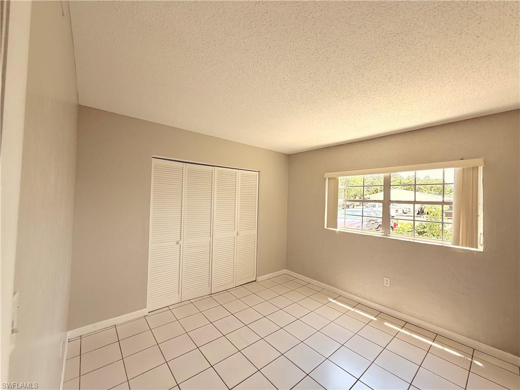 Neutral wall tones with white trim, ceramic tile flooring, and louvered closet doors