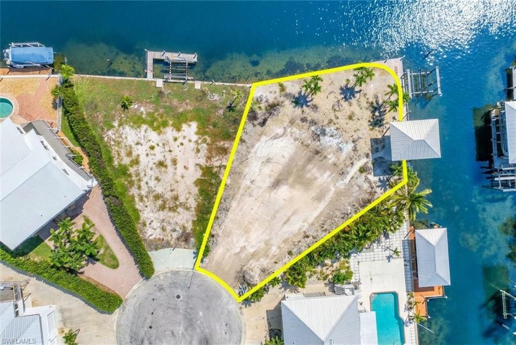 Waterfront parcel featuring a cul-de-sac entrance, mature palm trees, and direct water access - Virtually Edited Image