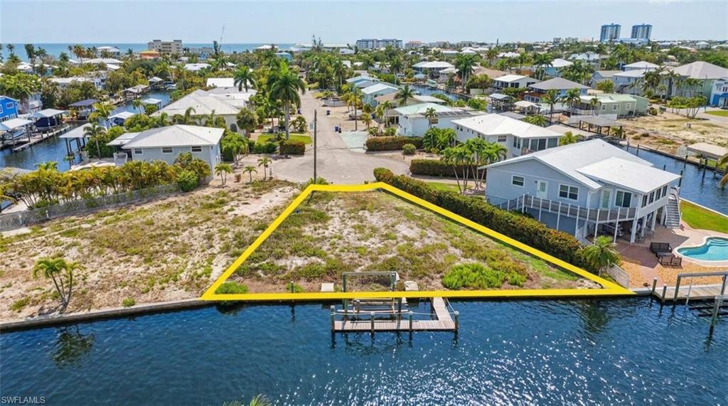 Vacant waterfront lot featuring a private dock structure and direct canal access - Virtually Edited Image
