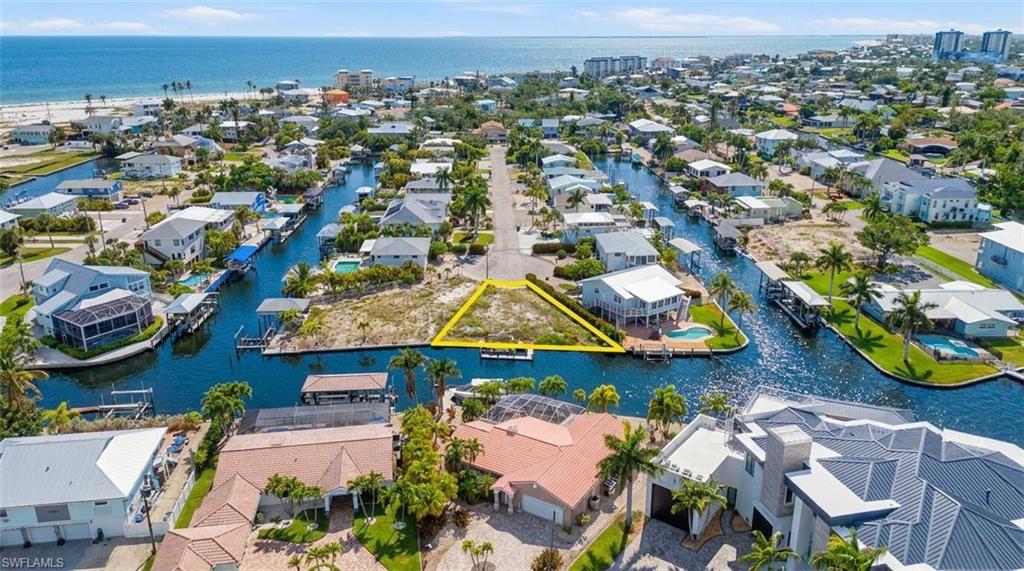 Vacant waterfront land parcel bordered by canals on two sides, featuring direct canal access, a triangular lot shape, and proximity to the open water - Virtually Edited Image