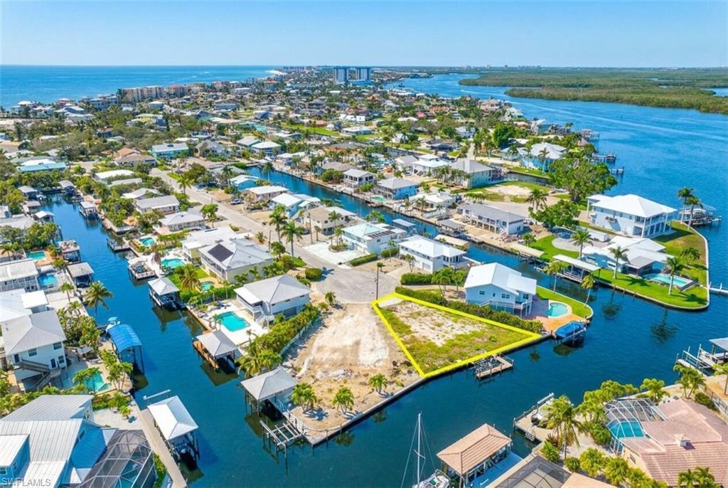 Waterfront property featuring direct canal access, a clear lot for building, and surrounded by developed residential properties - Virtually Edited Image