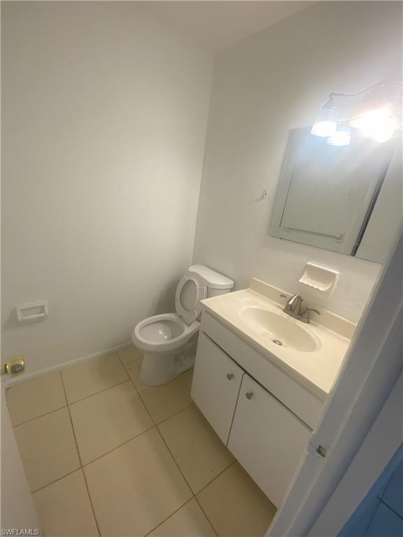 Bathroom featuring neutral tone tile flooring, a white vanity with an integrated sink, a chrome faucet, a wall-mounted medicine cabinet, and a two-bulb vanity light fixture