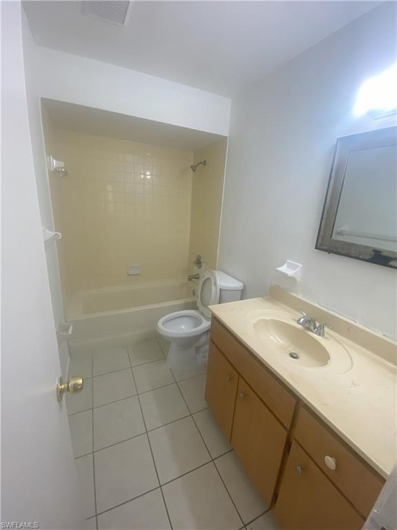 Bathroom featuring a tub/shower combination with tiled surround, a toilet, a vanity with an integrated sink, and wood-finish cabinetry
