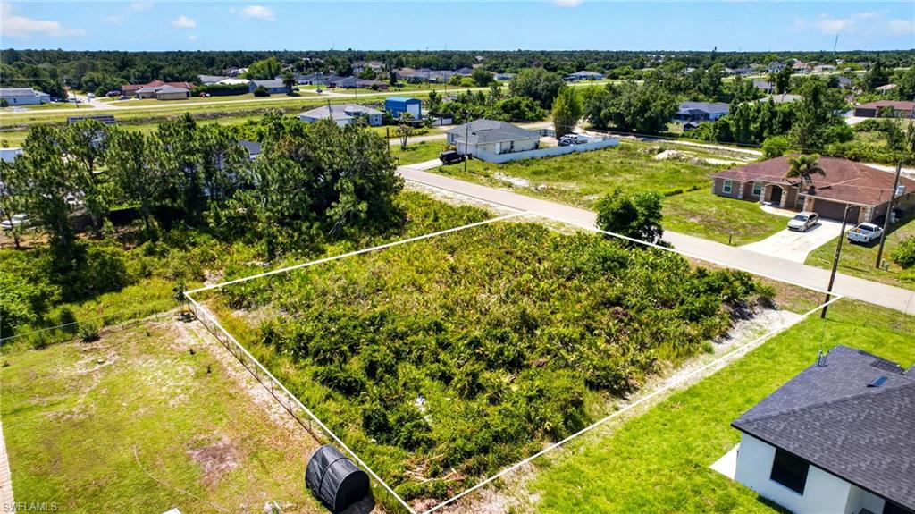 Expansive undeveloped lot featuring dense natural vegetation, a clear property boundary, and proximity to paved road access