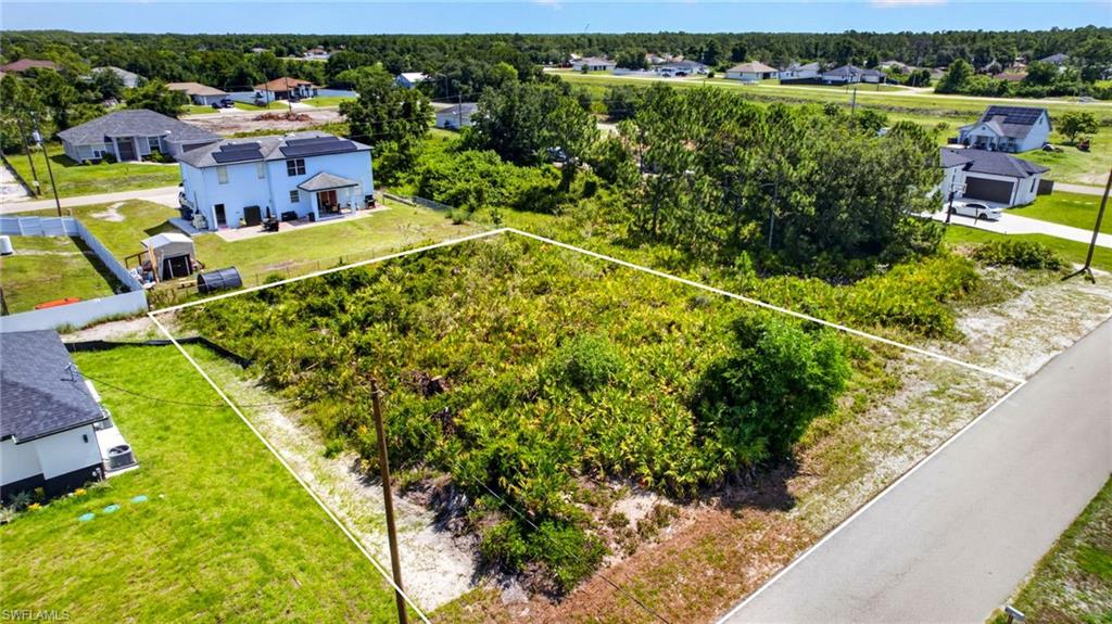 Cleared land parcel featuring natural vegetation, adjacent paved road access, and utility poles present
