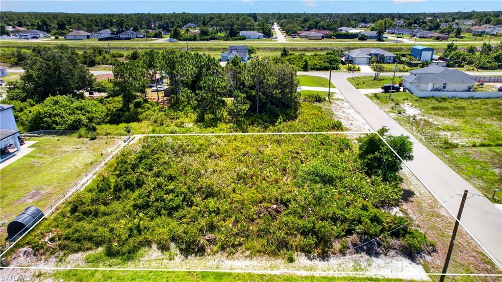 Vacant land parcel featuring established foliage and a paved road frontage
