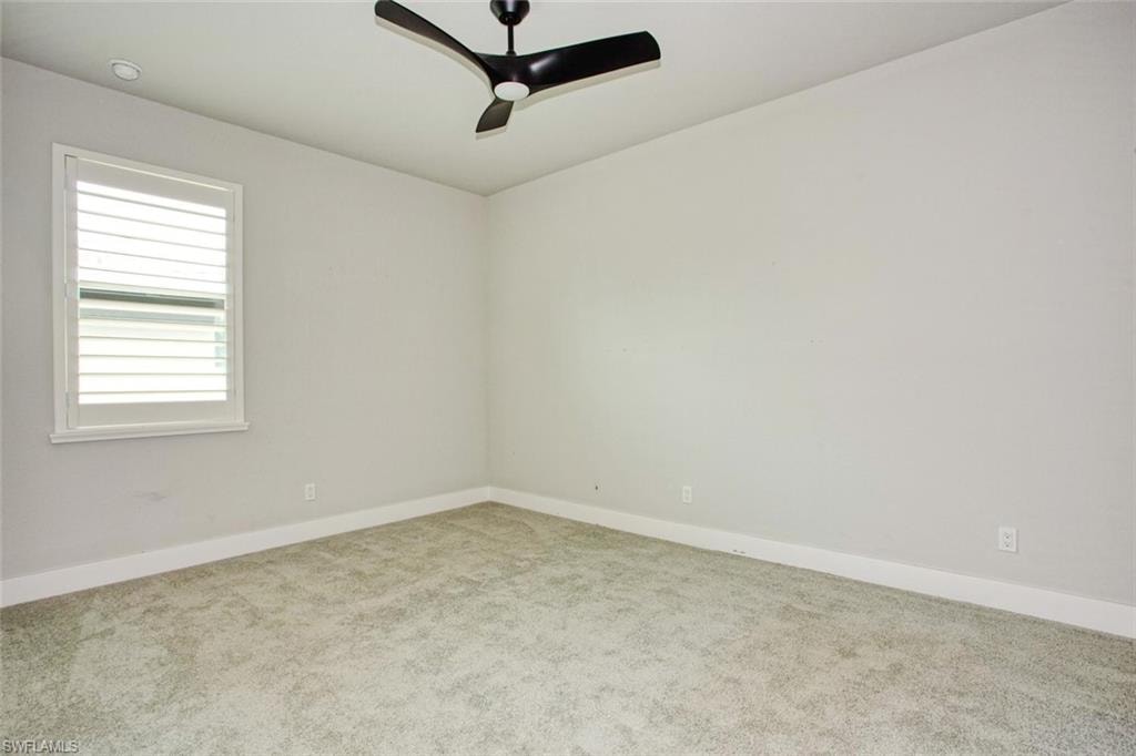 Carpeted room featuring a ceiling fan with black blades, a window with white louvered shutters, recessed lighting, and white baseboards