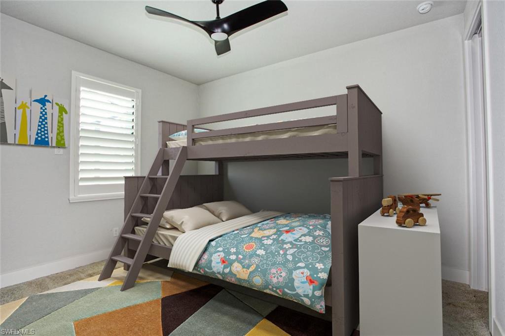 Bedroom featuring a white framed window with plantation shutters, a contemporary ceiling fan, and light-toned walls