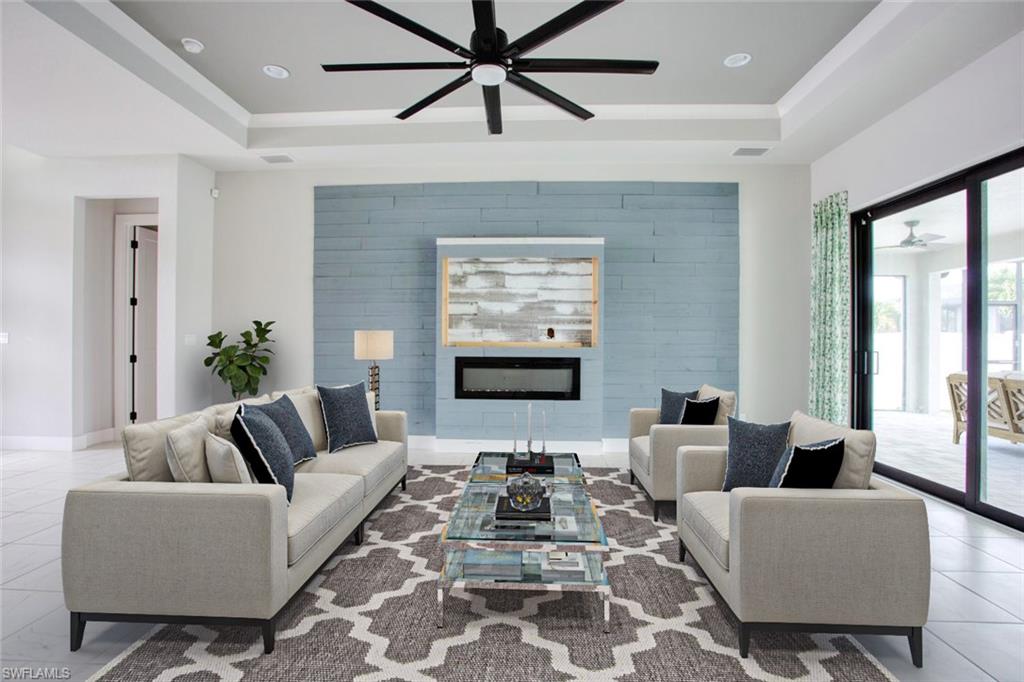 Spacious living area featuring a tray ceiling, recessed lighting, and a modern ceiling fan