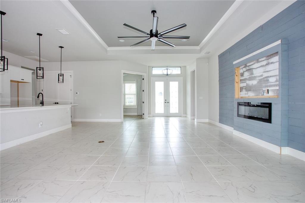 Spacious interior featuring large format floor tiling, a tray ceiling with a modern ceiling fan, and a contemporary linear fireplace
