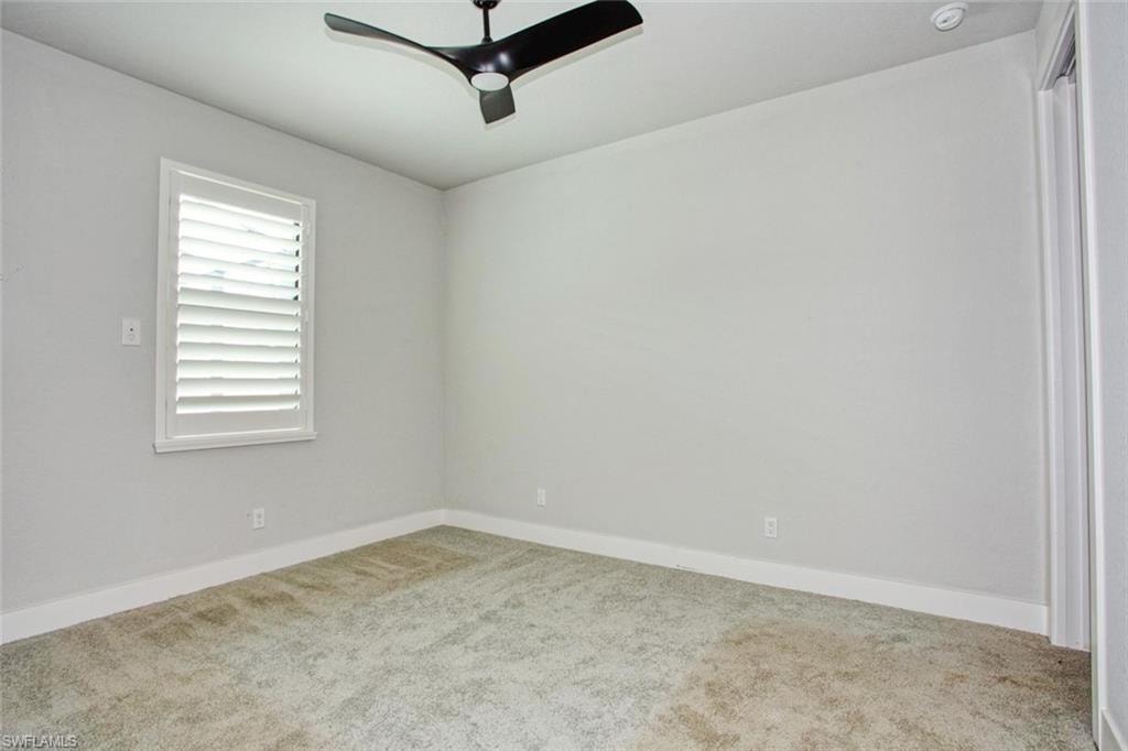 Recessed lighting illuminates this room featuring light-toned walls, white baseboards, and a modern ceiling fan