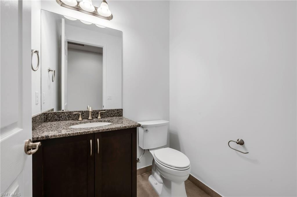 Powder room featuring a dark wood-finish vanity with a granite countertop, undermount sink, and brushed nickel fixtures