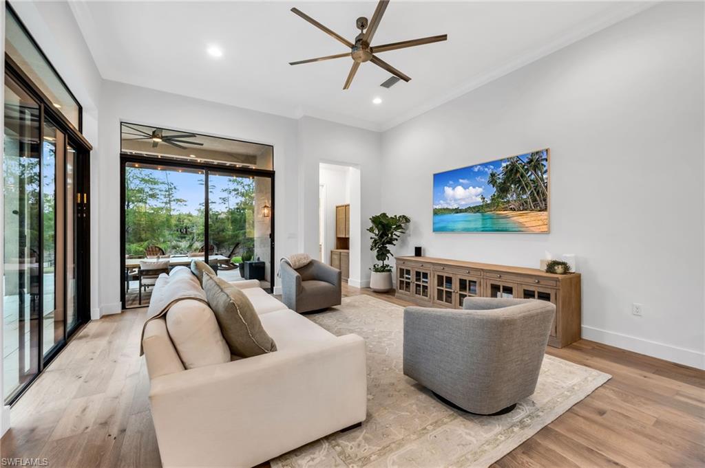 Spacious room featuring light wood-finish flooring, high ceilings with recessed lighting, and an overhead ceiling fan
