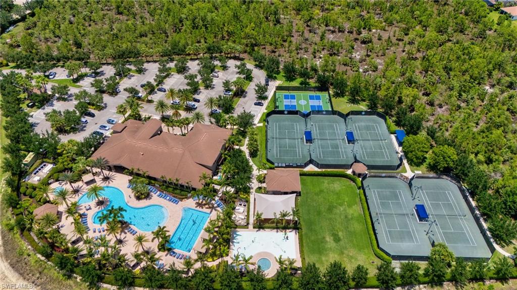 Expansive recreational area featuring a large clubhouse with a tile roof, multiple swimming pools, and a spacious parking lot