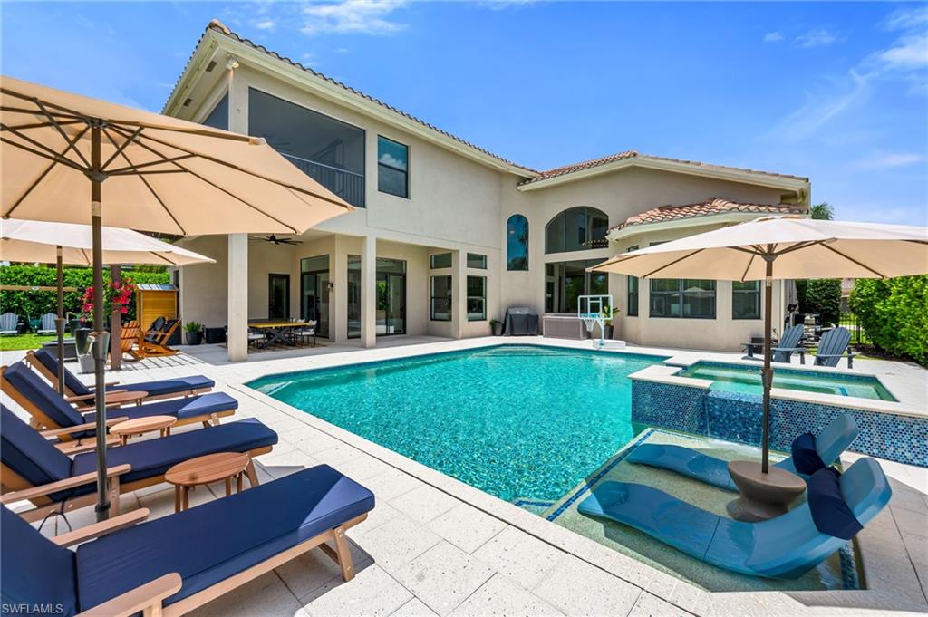 Expansive outdoor living area featuring a large swimming pool, integrated spa with mosaic tile