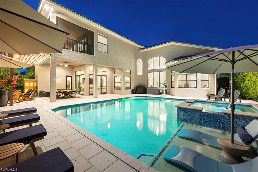 Expansive pool area featuring a swimming pool, integrated spa with decorative tile, and a large covered patio