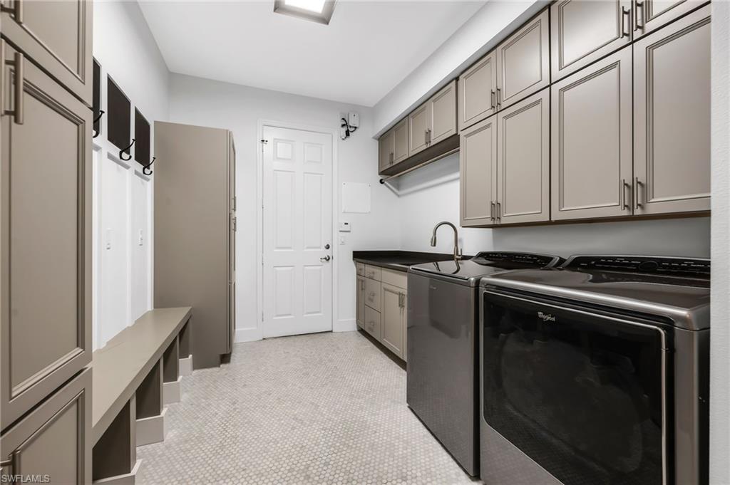 Spacious utility room featuring extensive built-in cabinetry, durable hexagon tile flooring, a utility sink, and a built-in bench with storage
