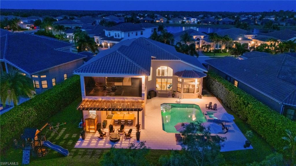 Expansive rear exterior featuring a screened balcony, covered pergola with recessed lighting, and a private swimming pool