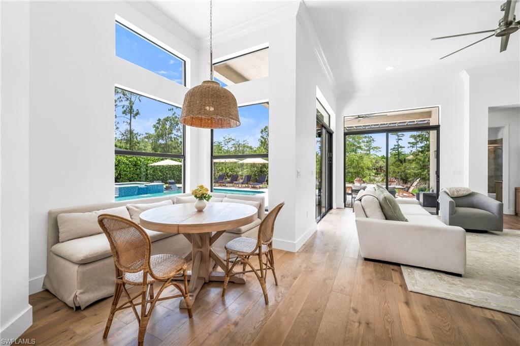 Breakfast nook featuring wood-finish flooring, high ceilings, abundant natural light through multiple windows, and a woven pendant light fixture