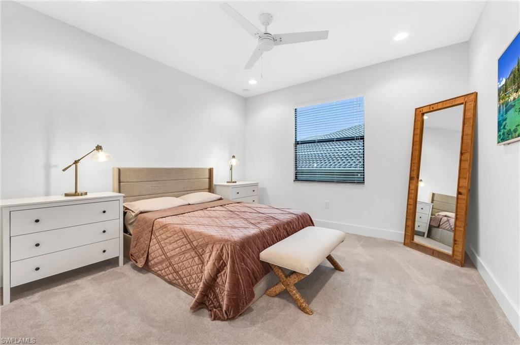 Carpeted bedroom featuring an upholstered headboard, a ceiling fan with integrated lighting, recessed lighting, and a window with horizontal blinds