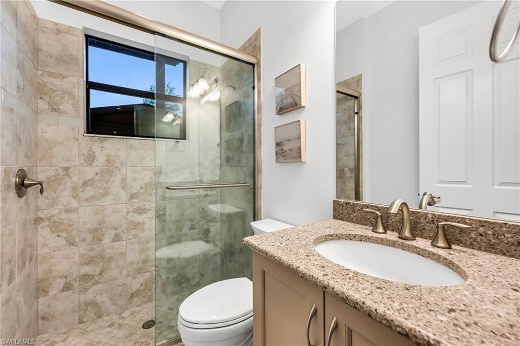 Bathroom featuring a glass-enclosed shower with tile surround and a window