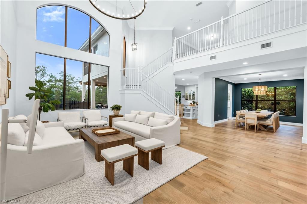 Two-story living area featuring extensive window walls, wood-finish flooring, and a contemporary chandelier