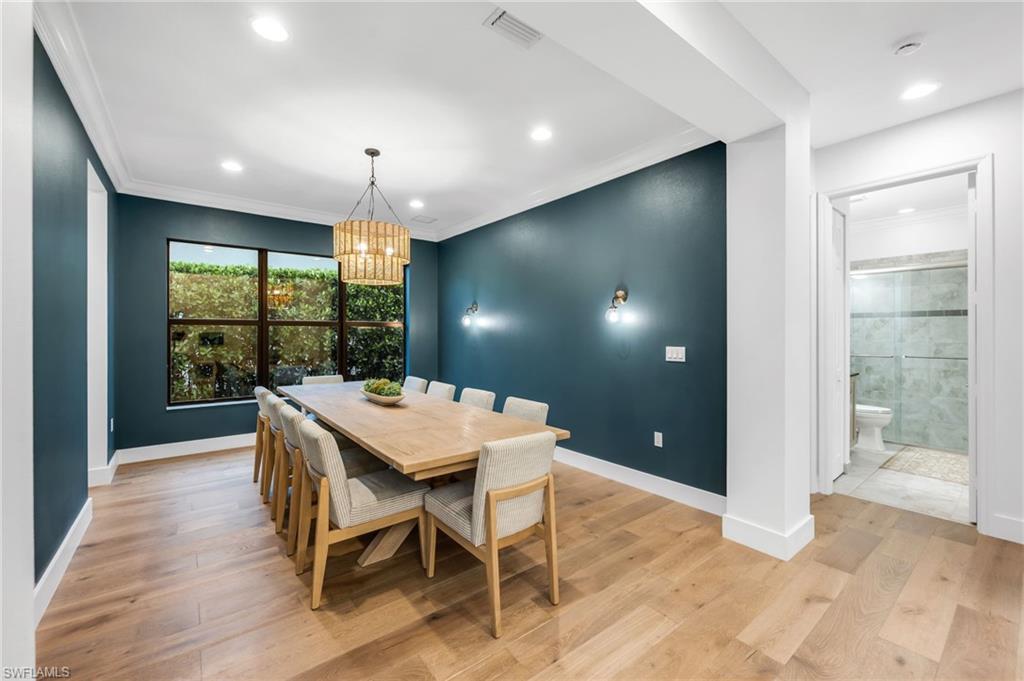 Spacious dining area featuring wood-finish flooring, a large window, recessed lighting, and a decorative chandelier