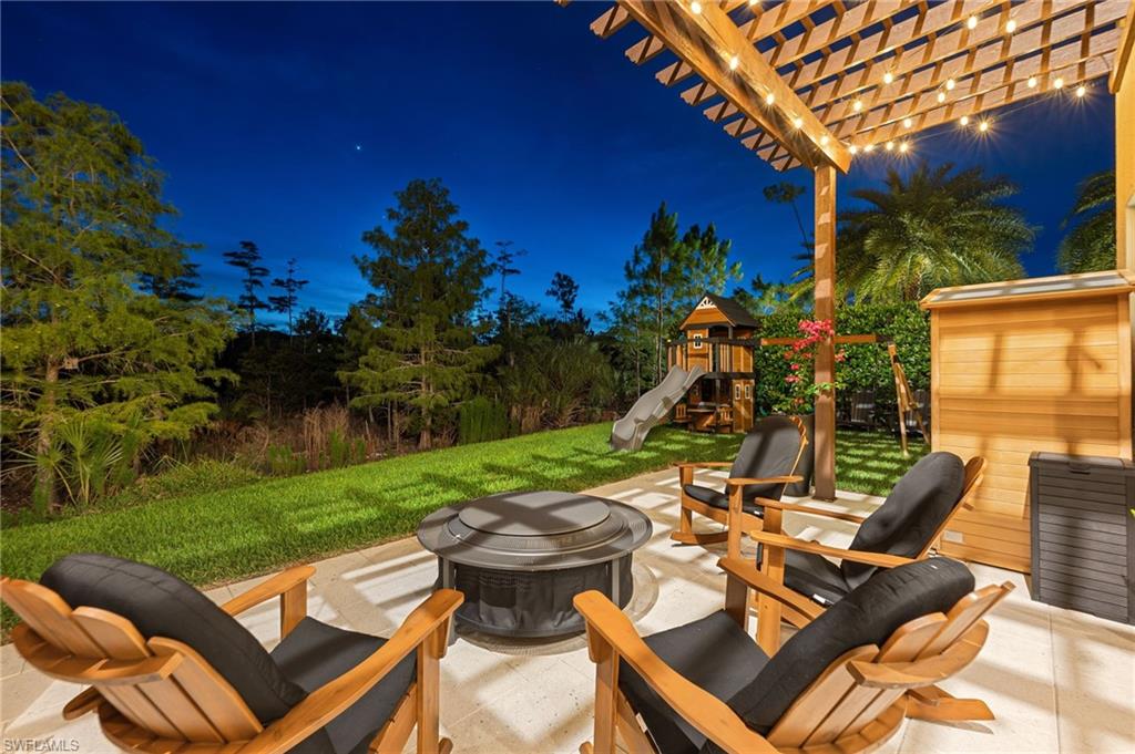 Outdoor patio featuring a wooden pergola with string lighting, a central fire pit, Sauna and playground