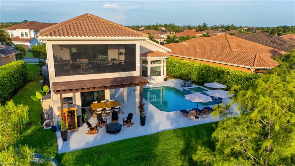 Rear exterior featuring a screened-in second-story balcony, an expansive patio, and an integrated pool with a spa