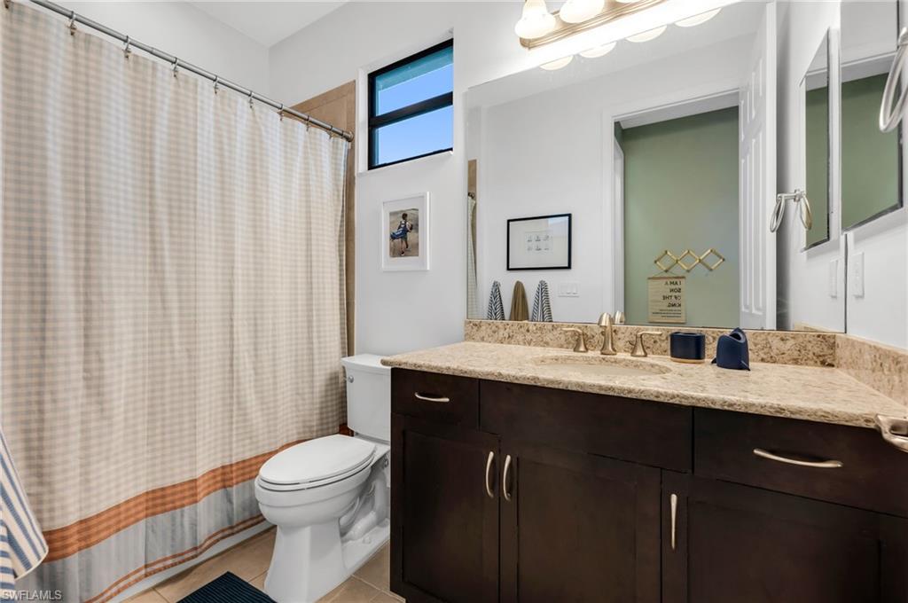 Bathroom vanity featuring a light-toned stone countertop, integrated sink, and dark wood-finish cabinetry with brushed nickel hardware