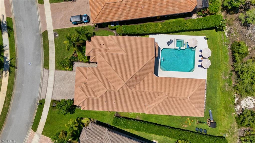 Aerial view showcasing a property with a tile roof, a private swimming pool, an integrated spa, and an expansive patio