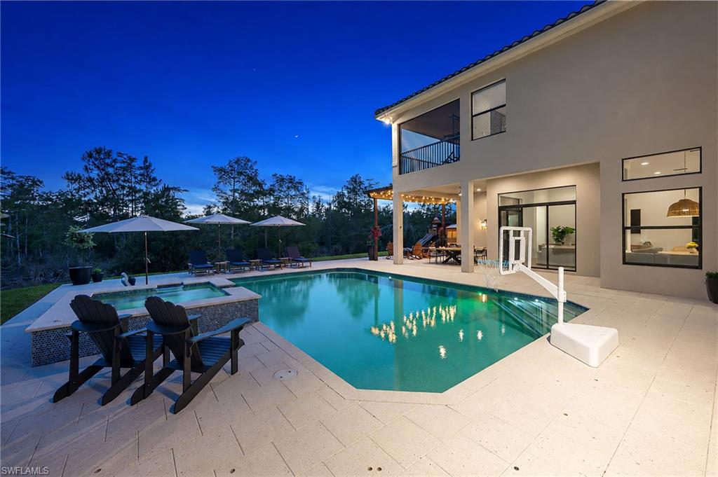 Rear exterior featuring a swimming pool, integrated spa, covered patio, and second-story balcony