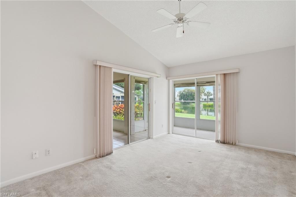Vaulted ceiling room featuring light-colored carpet, a ceiling fan, and two sets of sliding glass doors