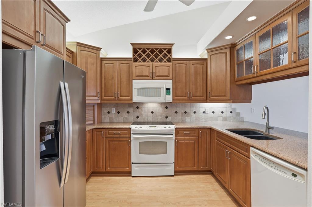 Kitchen featuring wood-finish cabinetry, speckled countertops, and a tiled backsplash