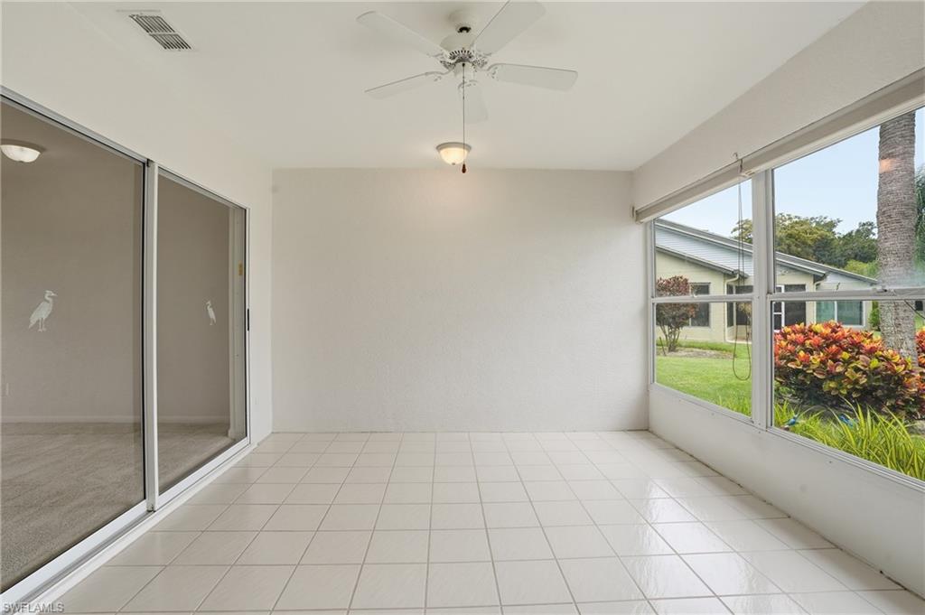 Screened patio featuring white tile flooring, ceiling fan, recessed lighting, and expansive windows overlooking landscaping