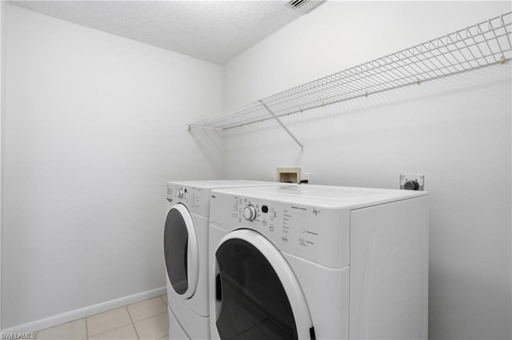 Dedicated utility area featuring a wire storage shelf, light-toned wall paint, and neutral tile flooring