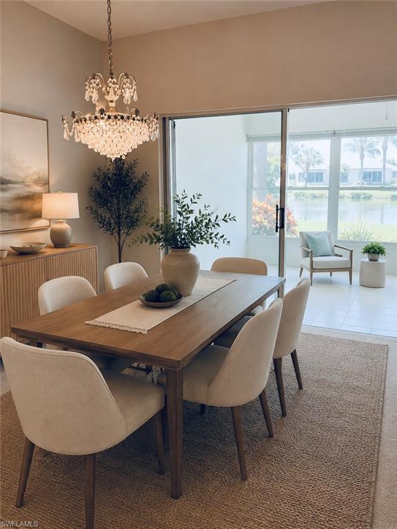 *Virtually Staged* Dining area featuring a crystal chandelier, wood-finish flooring, and sliding glass doors to a screened lanai