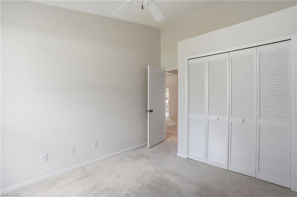 Plush carpet flooring, neutral wall tones, and a ceiling fan with light fixture