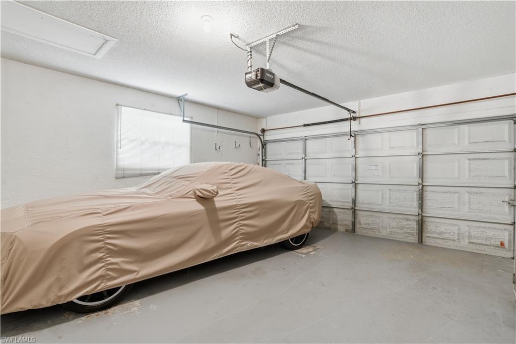 Two-car garage featuring a garage door opener system, overhead lighting, and a single window with blinds