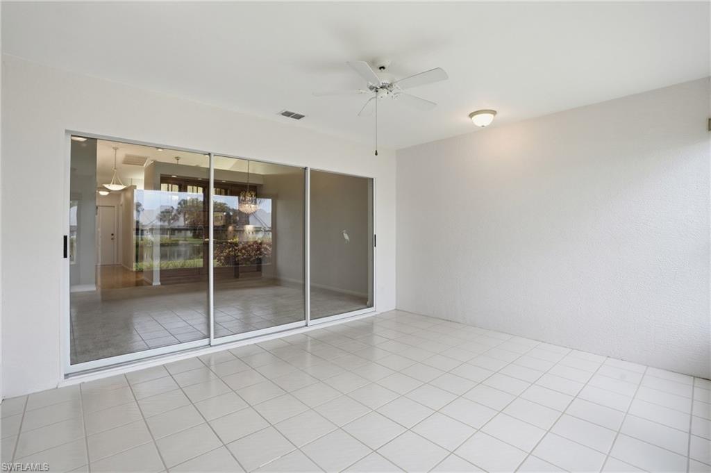 Spacious enclosed patio featuring large format square tile flooring and a ceiling fan