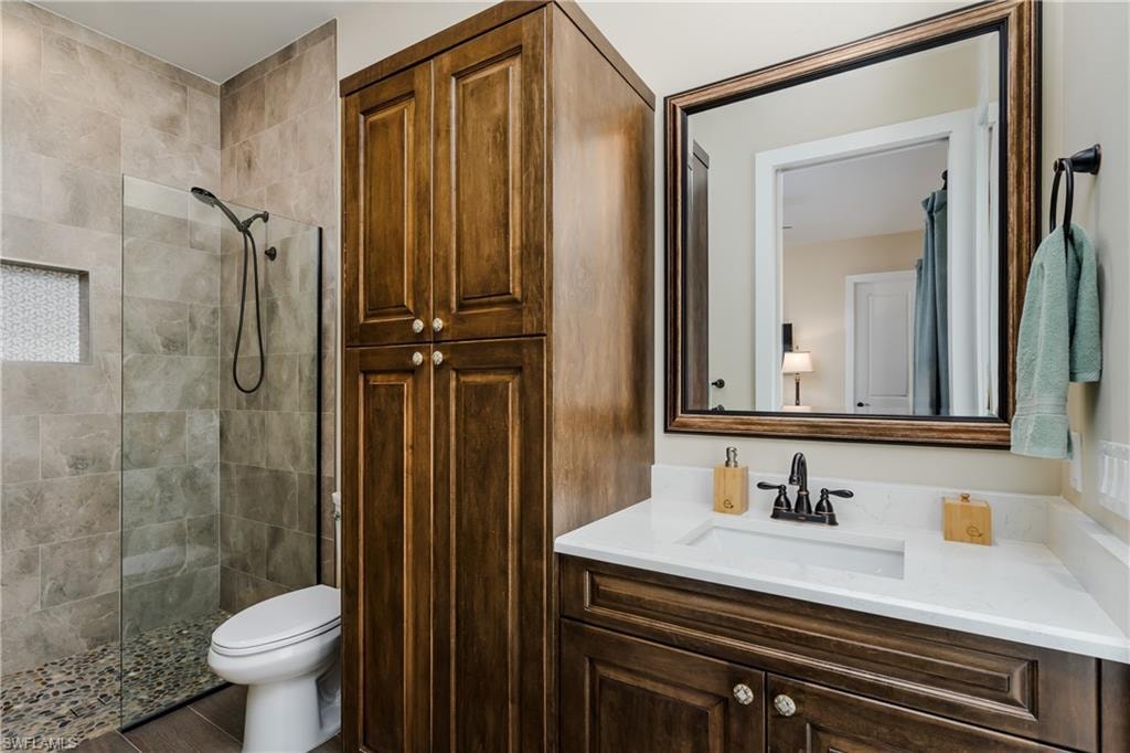 Bathroom featuring a walk-in shower with stone tile, a glass enclosure, and pebble flooring