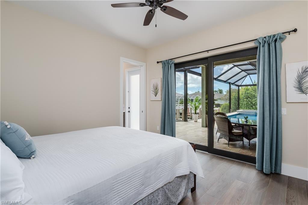 Room with wood-finish flooring and a ceiling fan, featuring sliding glass doors opening to an outdoor screened enclosure
